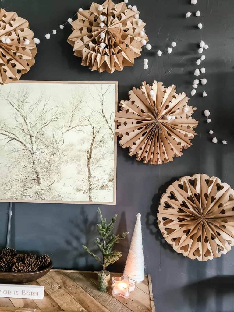 Garland made with fishing line and cotton balls with paper bag snowflakes hanging on dark gray painted wall around TV in boho living room