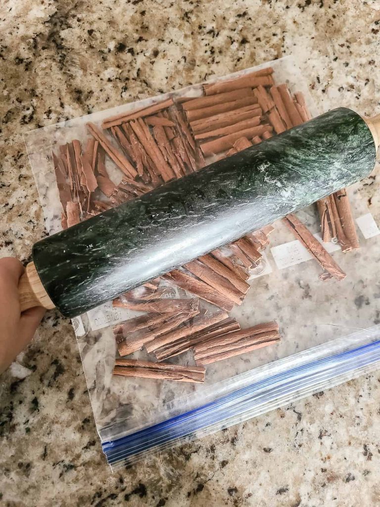 Using a rolling pin to crush cinnamon sticks in a plastic bag to put into a ornament for Christmas