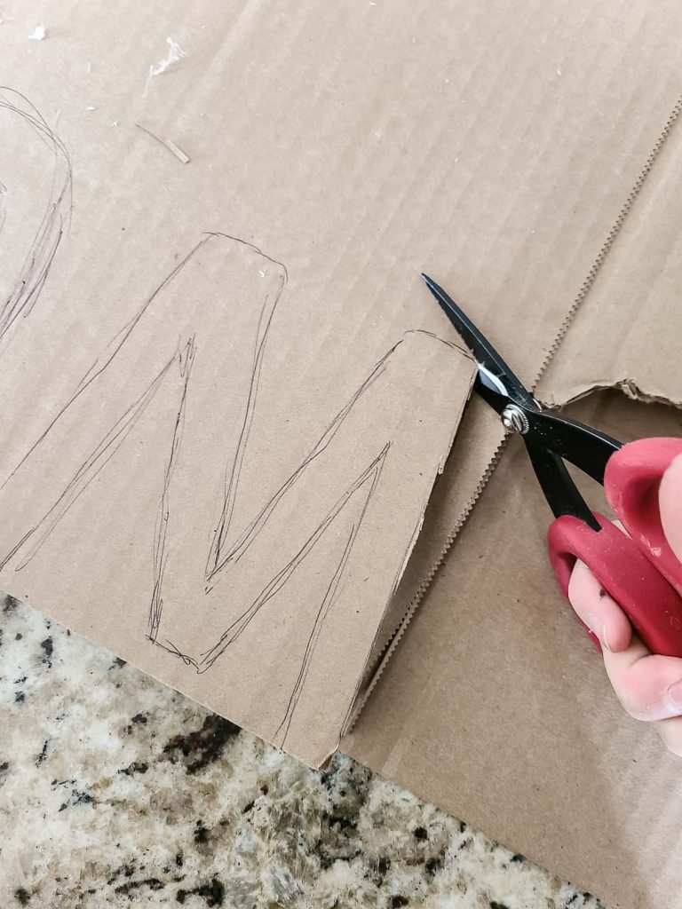 Cut out the letters from cardboard with scissors to make DIY stocking initial tags