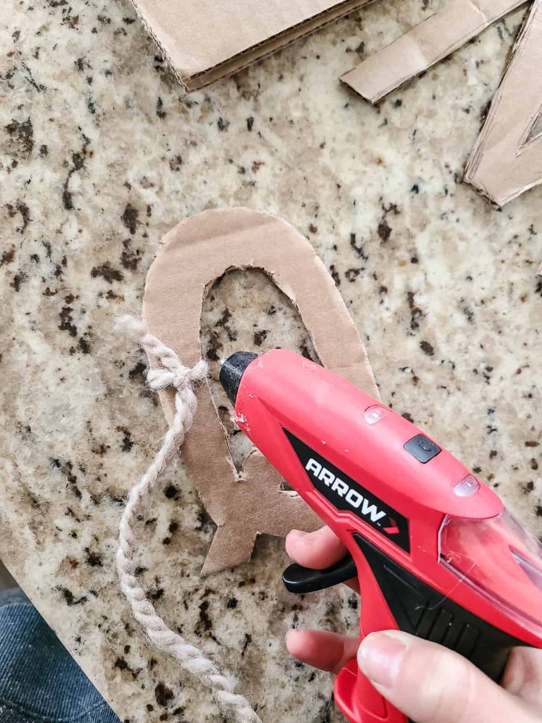 Use hot glue gun and yarn wrapped around the cardboard letters to make your do it yourself boho stocking labels