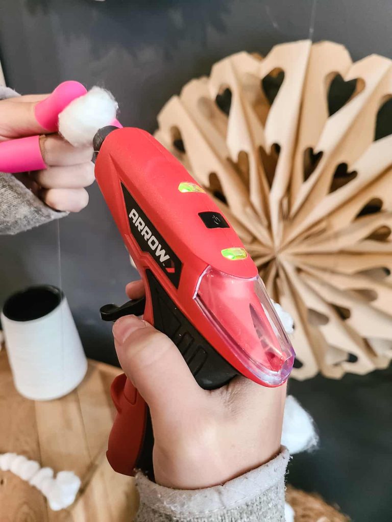 Hot glue gun to secure cotton ball into place on fishing line to make garland