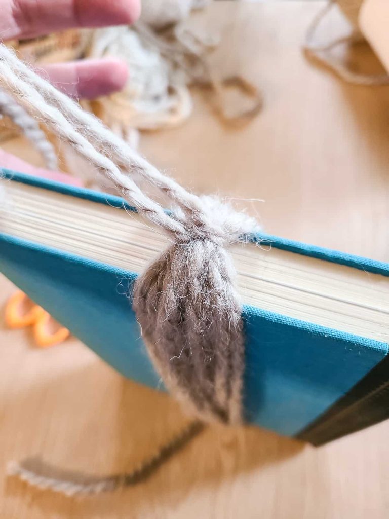 tying a knot in yarn at the top of the tassel to secure