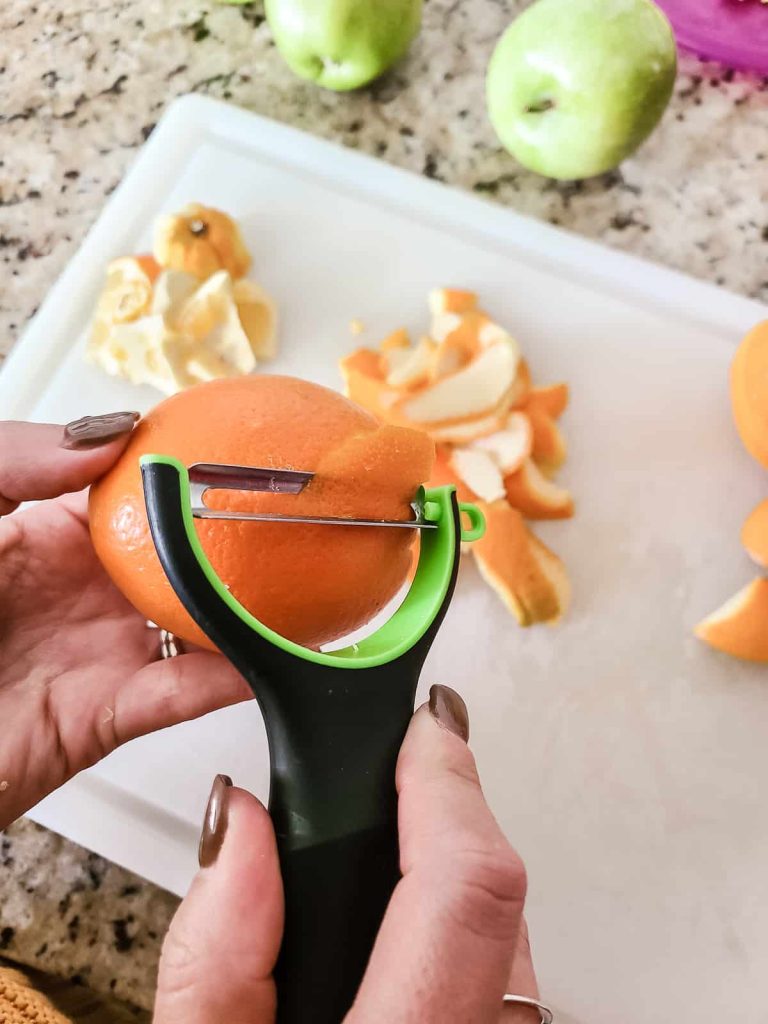Peeling an orange with a peeler is a great way to make your own dried orange peel and is much cheaper than buying from the store