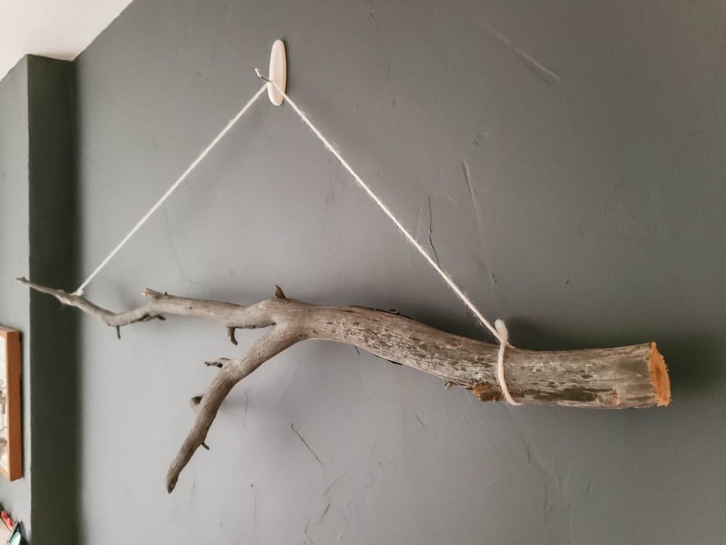 stick hanging on the wall with a command hook and string