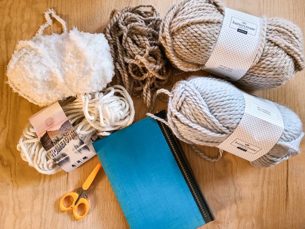 supplies for diy yarn tassel including yarn, book and scissors