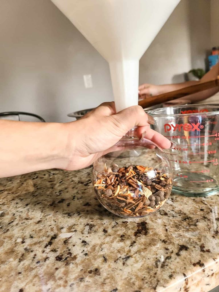 Using a funnel to put the mulling spices into a Christmas ornament to be given as a present for family