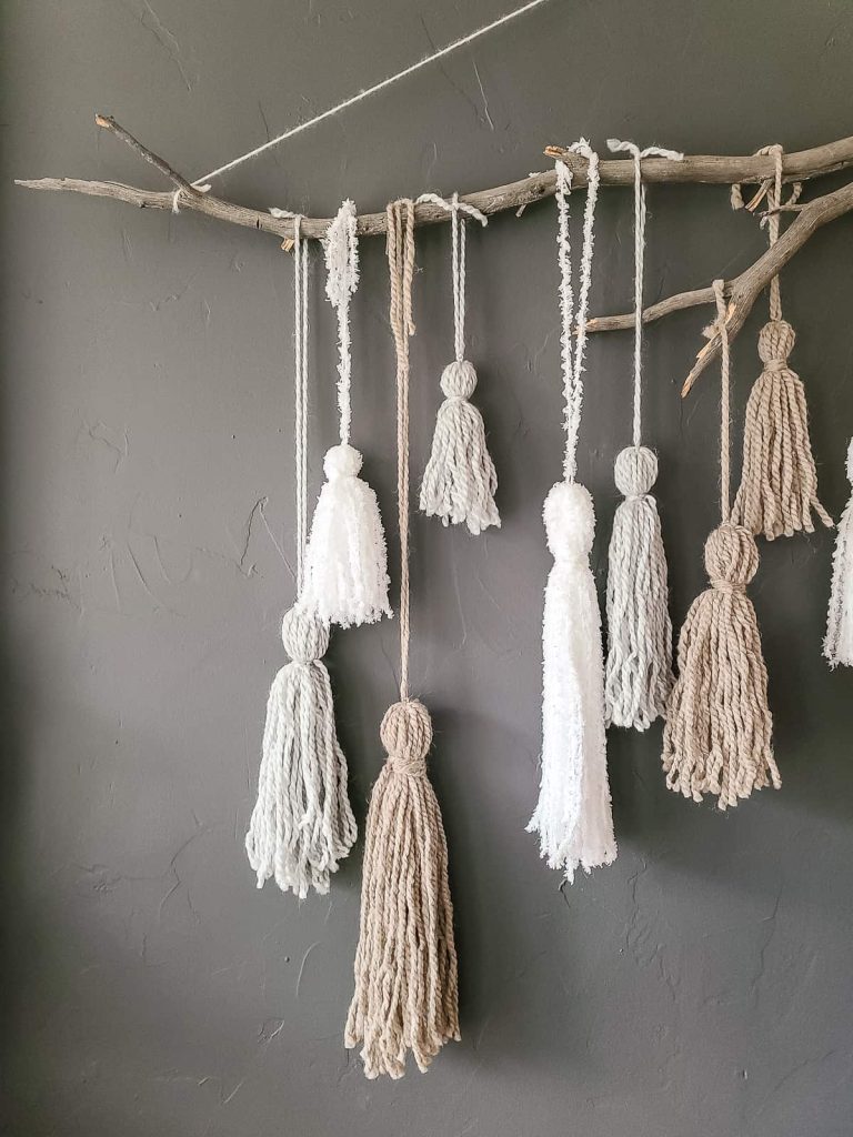 yarn wall hanging with stick and different size tassels made with yarn