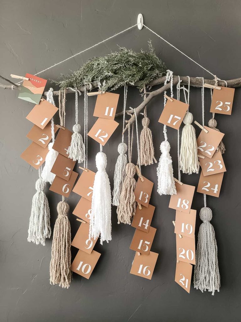 Yarn tassels hanging from stick with advent calendar cards clipped to the strands to countdown to christmas