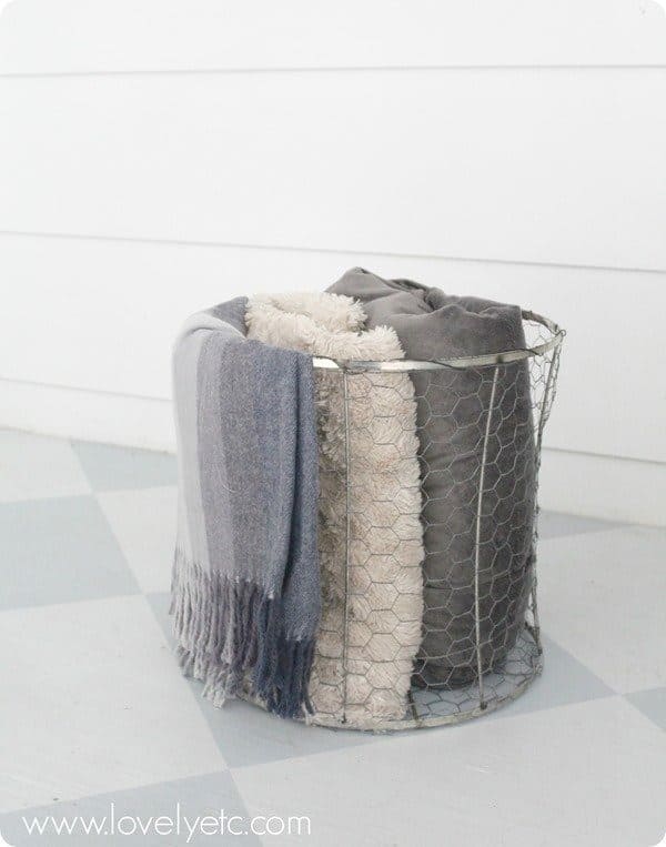 wire basket made from a lampshade and chicken wire being used to store blankets