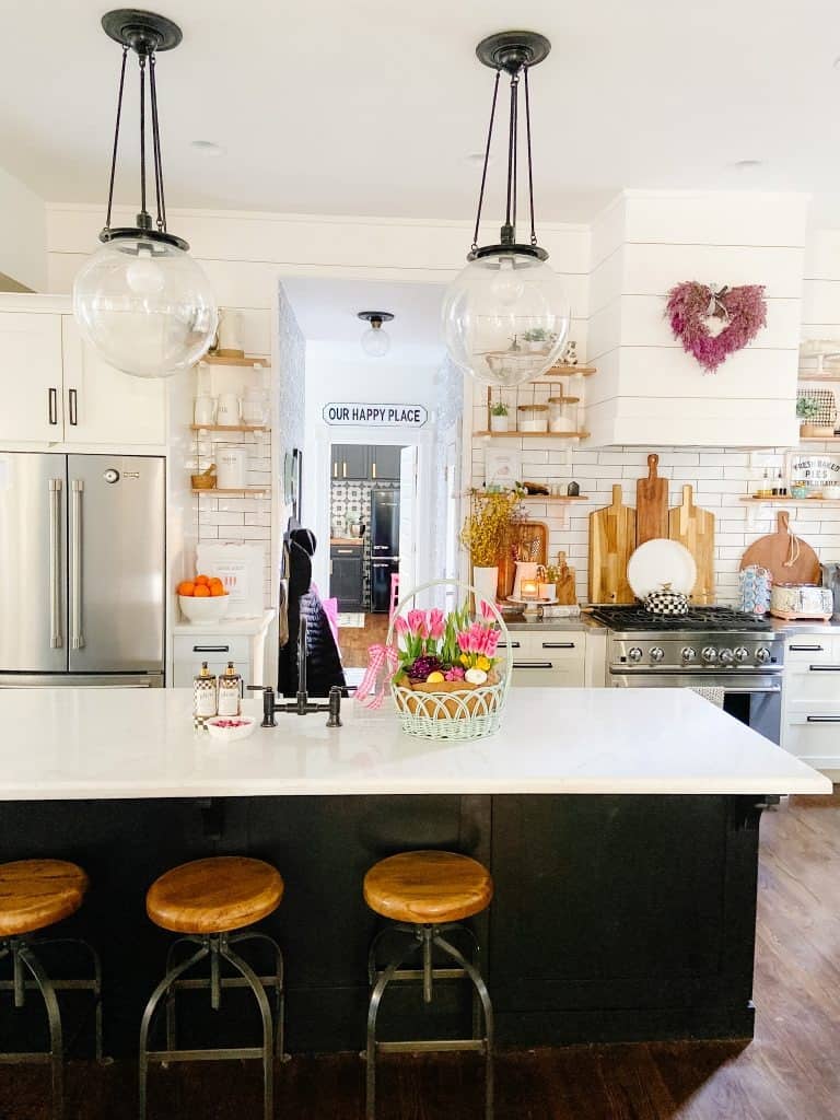 open kitchen with white subway tile blacksplash, stainless steel appliances and a dark kitchen island 