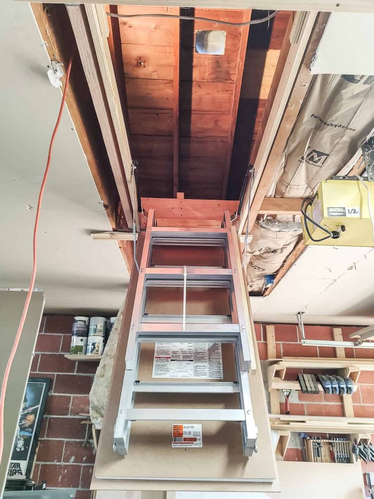 Unfolding an attic ladder to screw in temporary screws on the sides to square and prep for lag screws