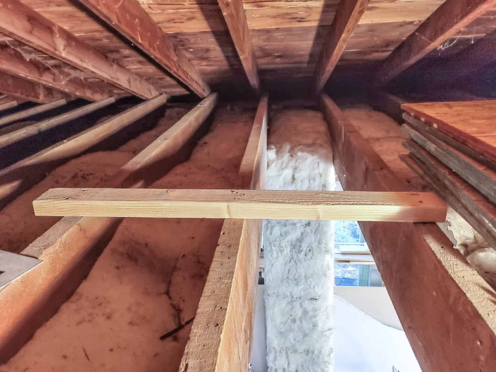 Using a scrap piece of 2x4 is a great way to temporarily support a joist that will be cut to make space for an attic ladder