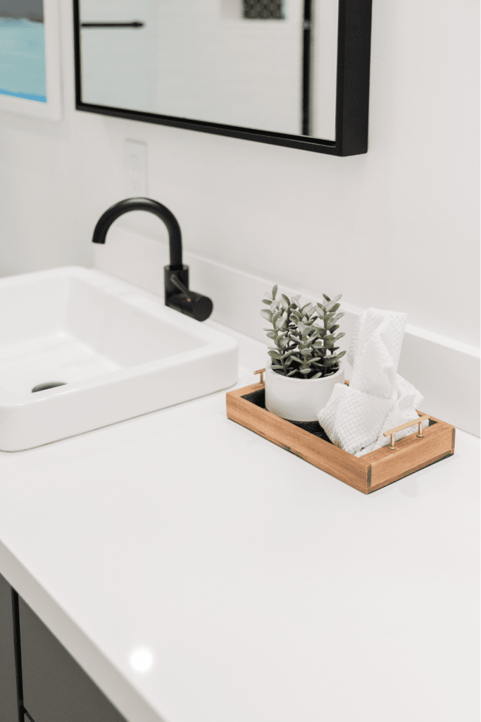 Keep decorations minimal in a bathroom to keep it feeling clutter-free. A simple wooden tray with a plant and white washcloth is all you need on your bathroom counter.
