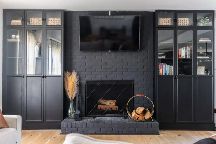 Bring a moody vibe to your living room by painting your fireplace and bookshelf cabinets with a dark pain color, like Behr Black