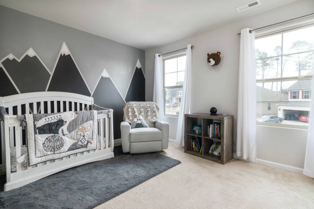 gettin creative with a large accent wall that has a design painted on it in a neutral nursery