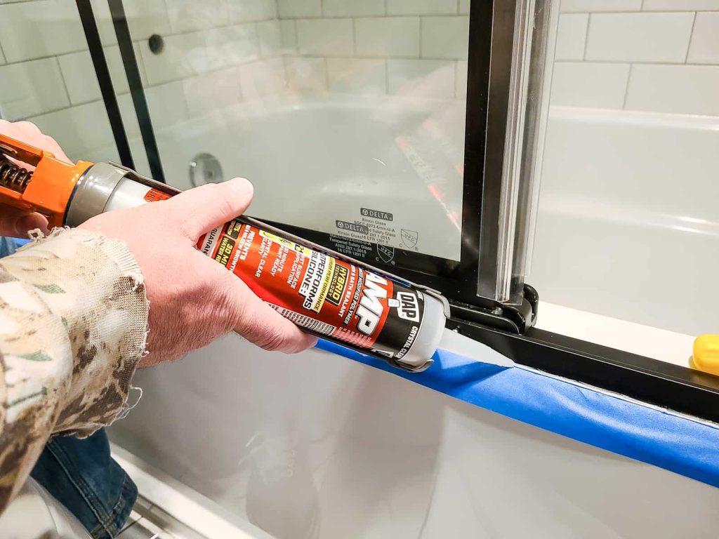 Applying the Dap AMP at a 45 degree angle on the tape and shower door to create a water proof seal