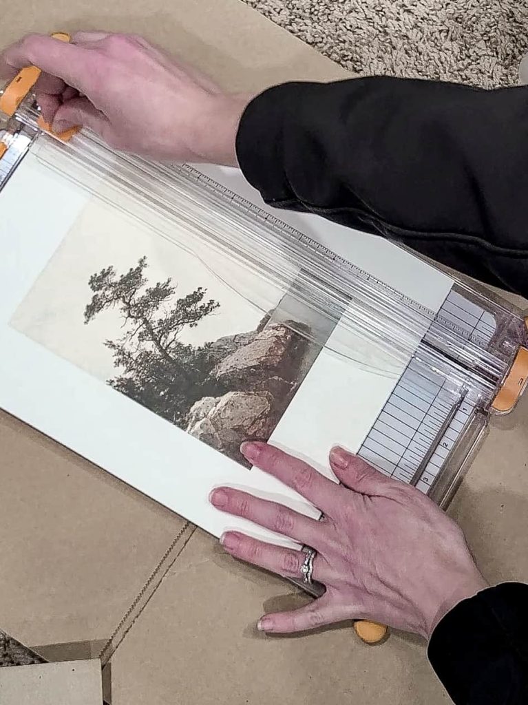 Cutting the textured paper with a print on it to size to fit into a frame with a paper cutter