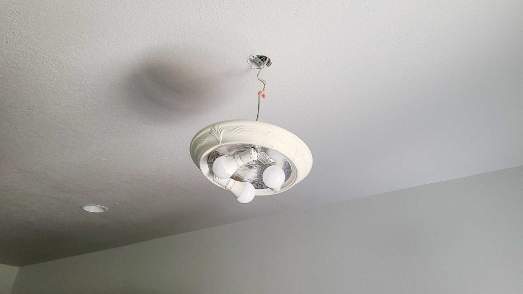 Picture of a ceiling light that is pulled down and ready to disconnect wires for a replacement