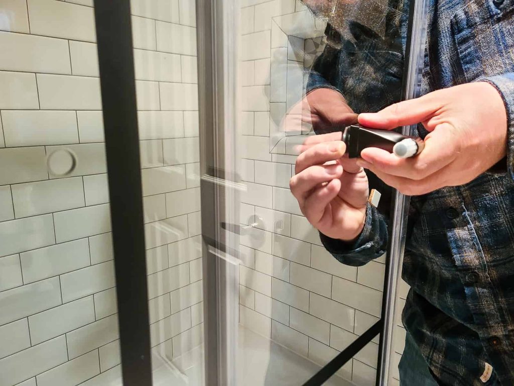 Installing the towel holder handles in the predrilled holes in the tempered glass panes