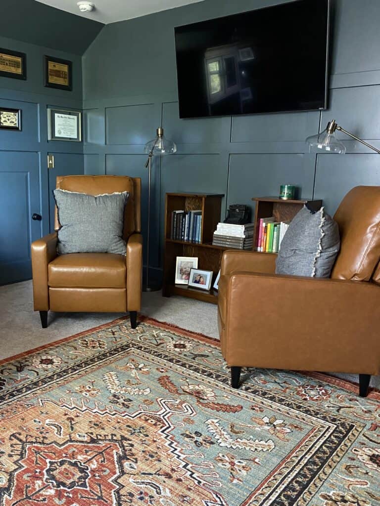 behr brooklyn paint color used in a home office / library with leather accent chairs with board and batten treatment on walls 