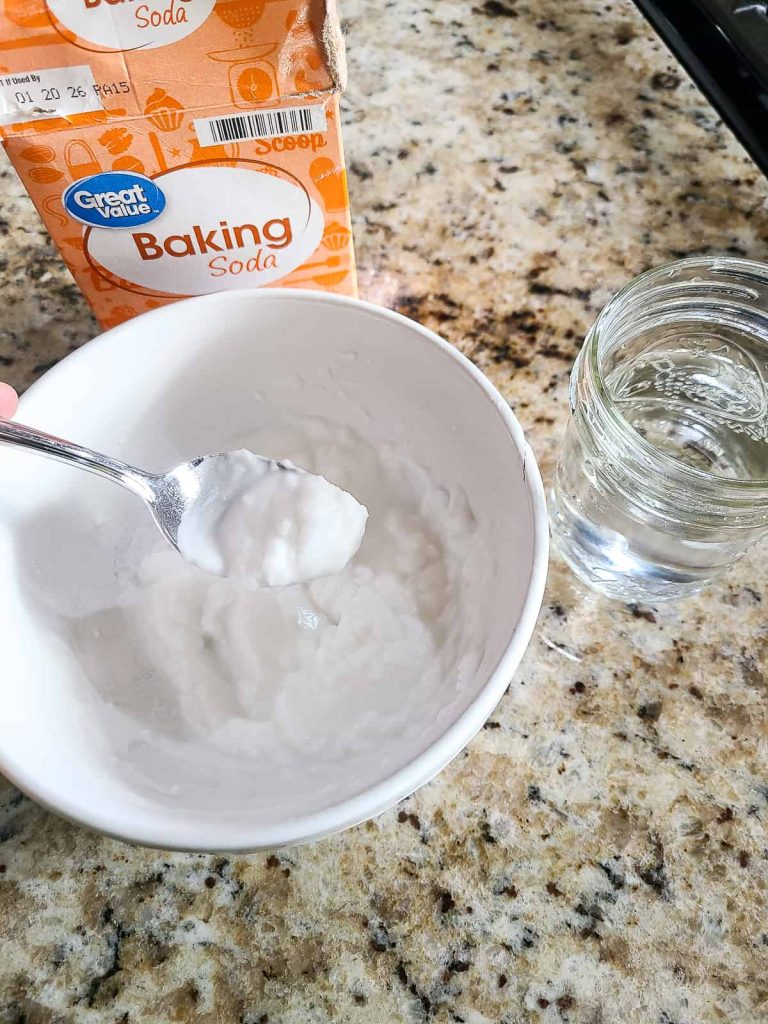 Creating a cleaning paste with warm water and baking soda for a how to clean a gas stove tutorial