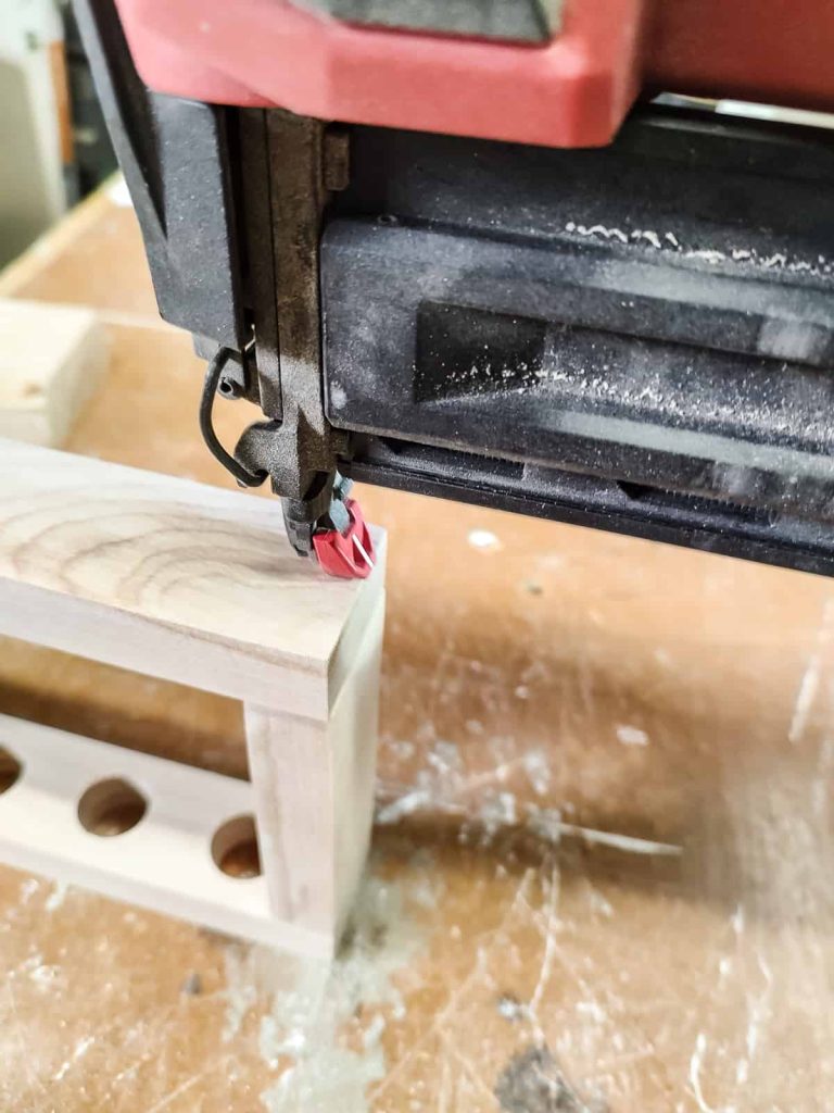 A brad nailer joining together two pieces of wood that are a part of a diy propagation stations.