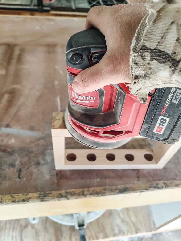 sanding down the wood filler to make the surface flush with the rest of the piece