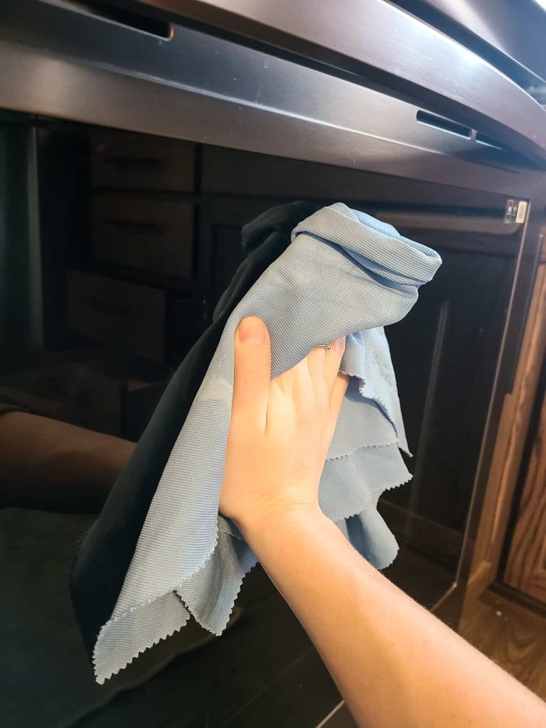 Cleaning the exterior of the oven door with a cloth and making sure the gas oven is clean inside and out