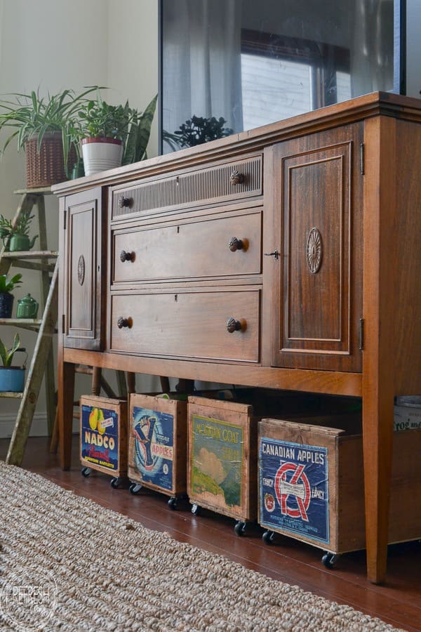 vintage crates on wheels under a console for toys
