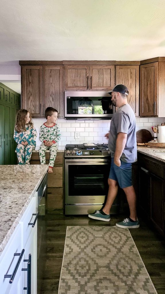 A man standing and 2 children sit beside Samsung's bespoke gas range