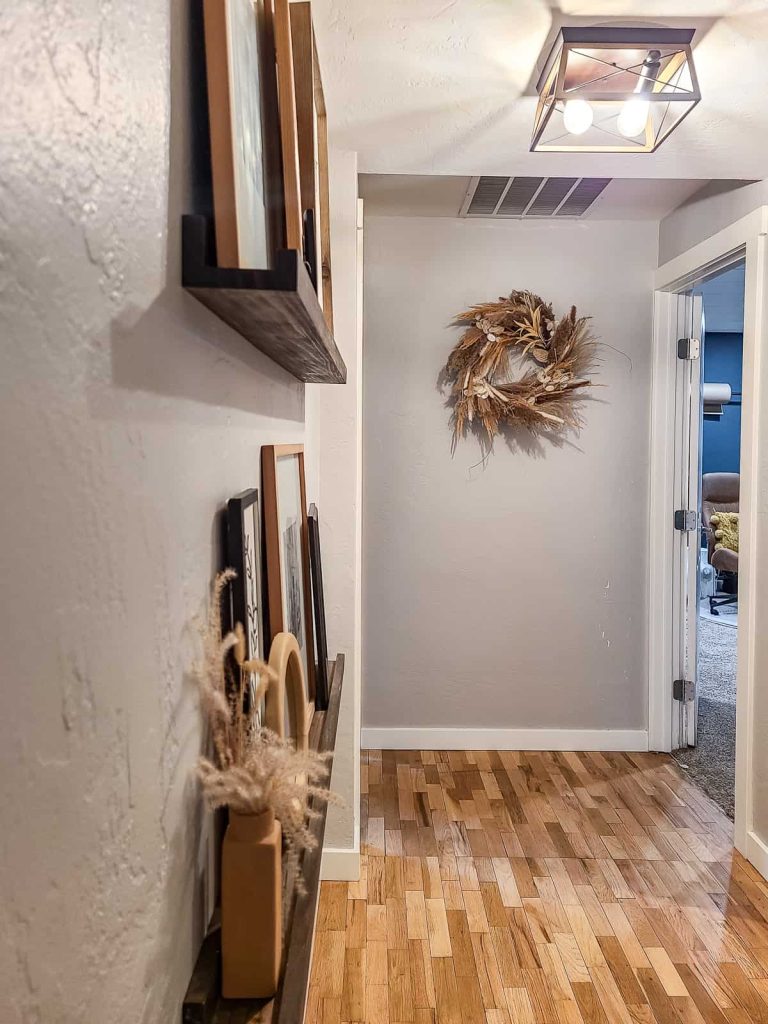 A finished product of a mixed pampas grass wreath hanging on the wall in hallway