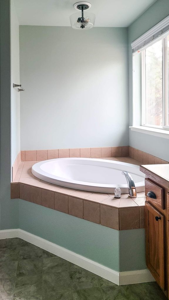 A beautiful photo of a bathtub with walls painted with Behr Riverdale light green paint color