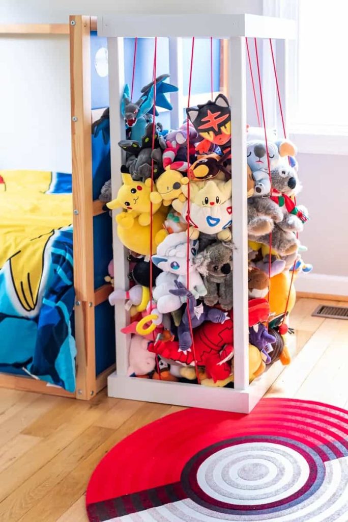Stuffed animals stored in DIY stuffed animal zoo made with wood and cord.