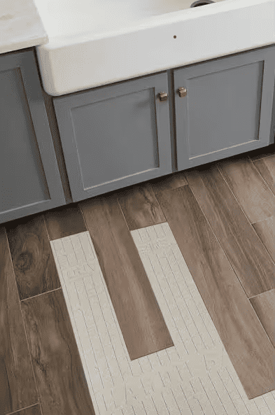 A photo of the floor with a cabinet on the side showing Hardiebacker underneath the flooring