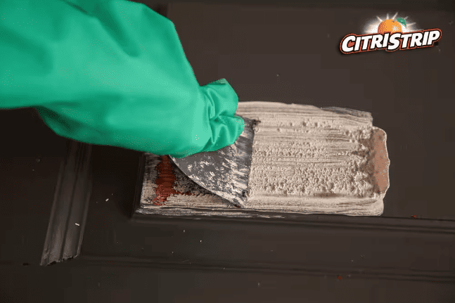 photo using a wooden scraper to gently scrape off the softened sealer and paint after using CitriStrip