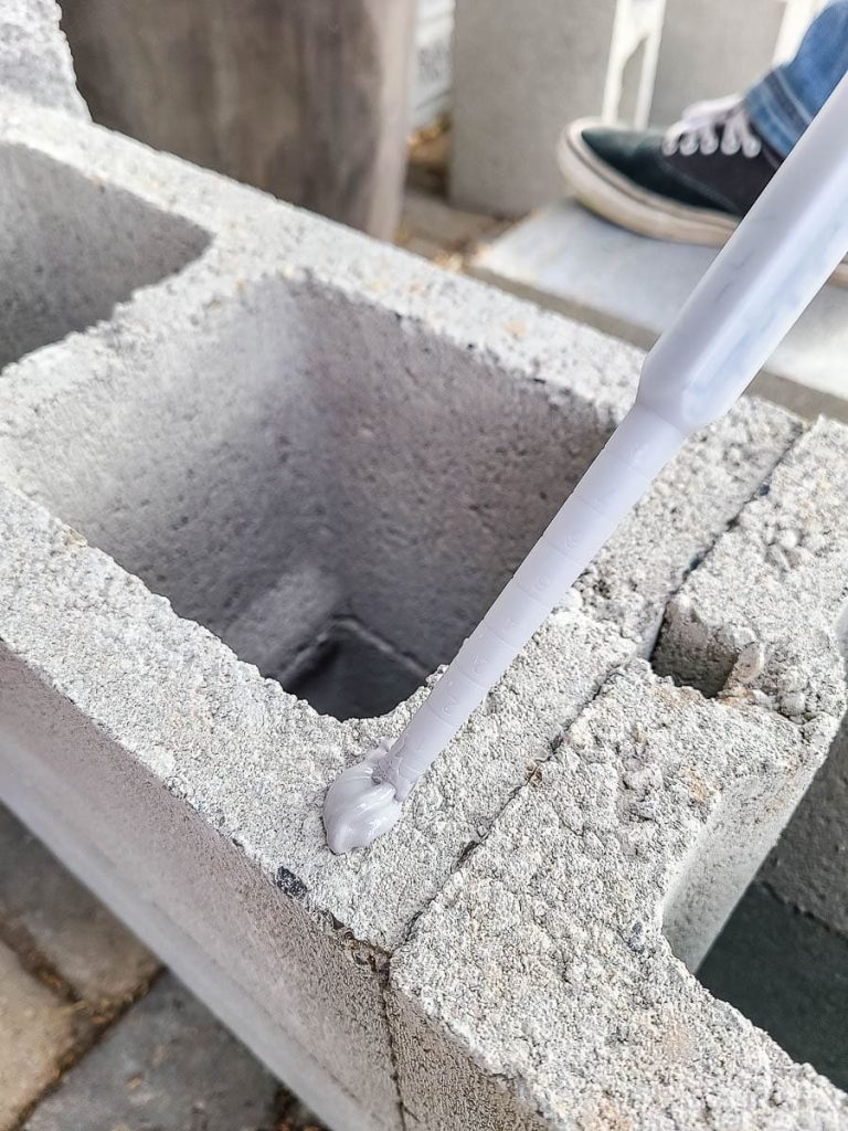 The photo shows the holes in second layer of concrete blocks facing up, and then more adhesive added to the top edge.