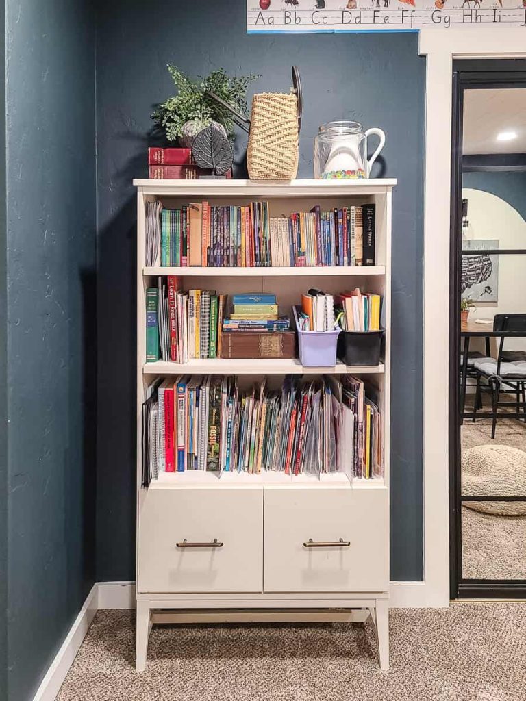 Organized bookcase full of picture books, chapter books and homeschool curriculum in homeschooling room