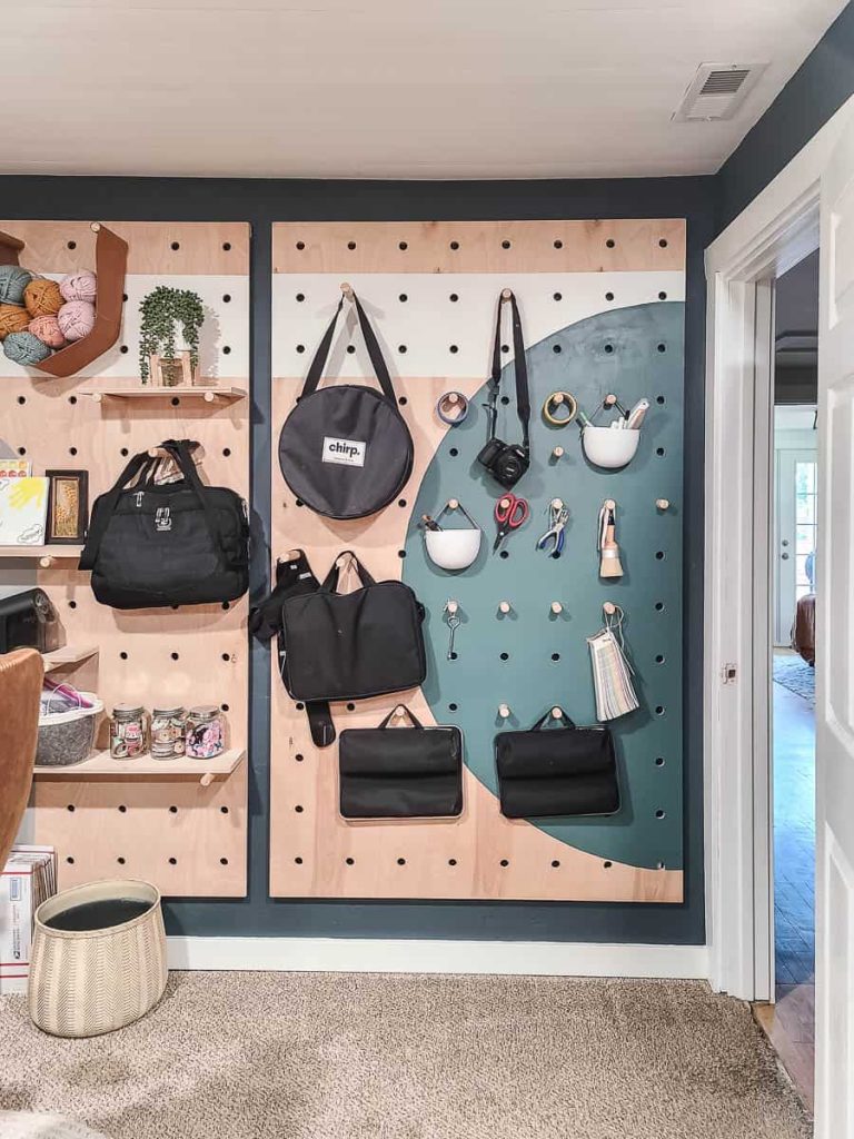 An interior view of a room featuring a pegboard wall and DIY wooden shelves, showcasing an organized and functional storage solution.