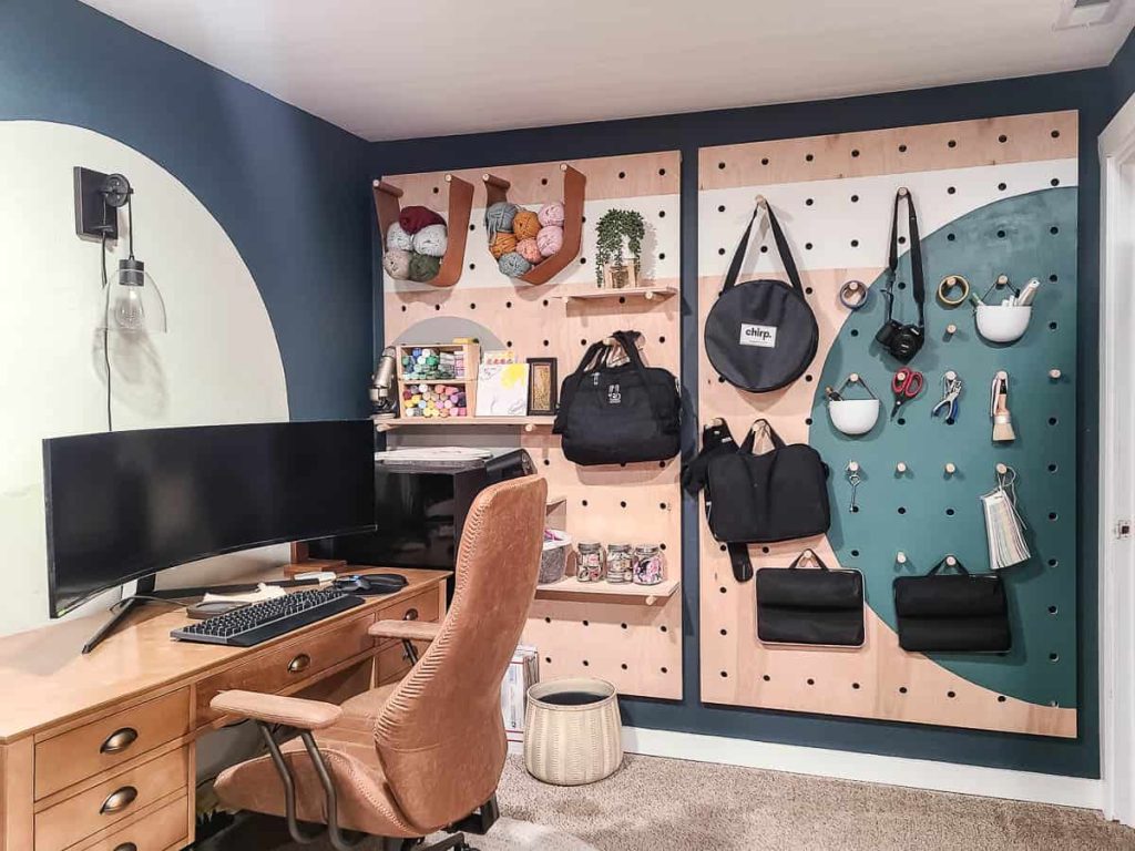 An office space featuring a room filled with DIY wooden shelves, a desk, a high chair, and a computer, creating a cozy and organized work environment.