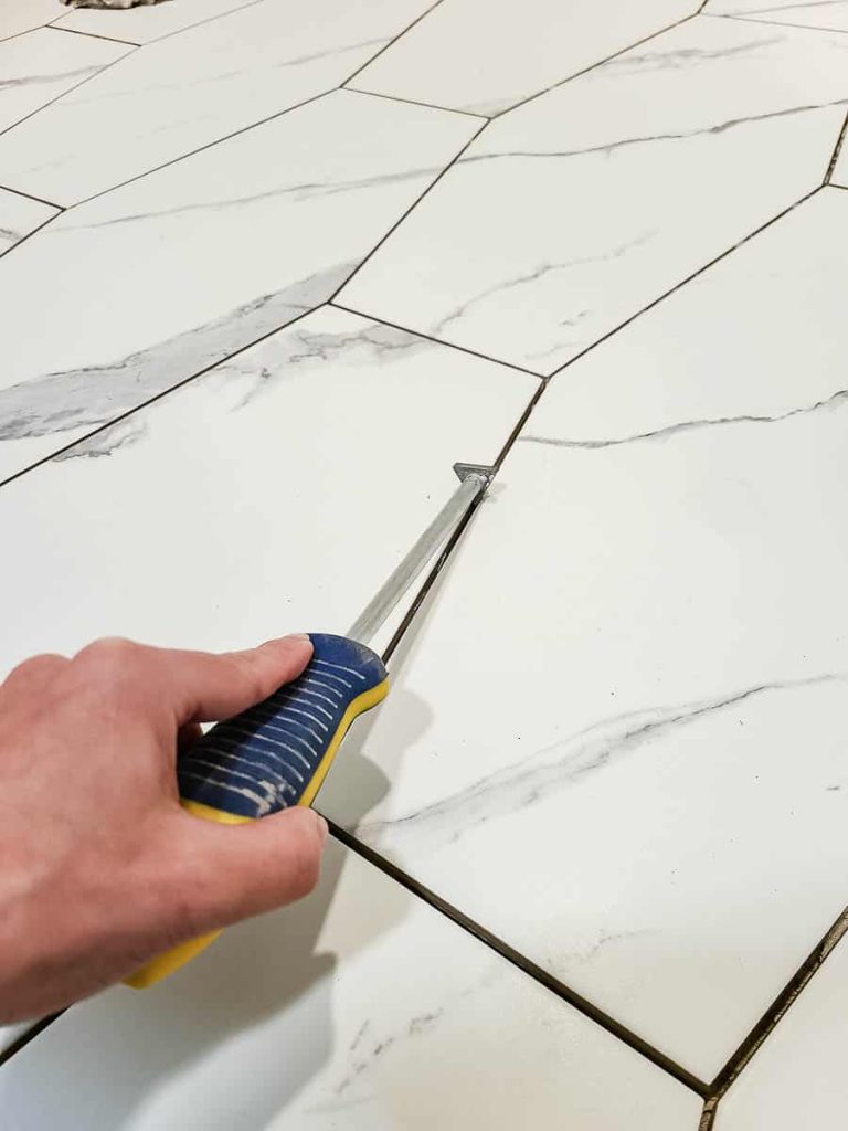 Image of a tile scraper being used on tiles prior to grouting.