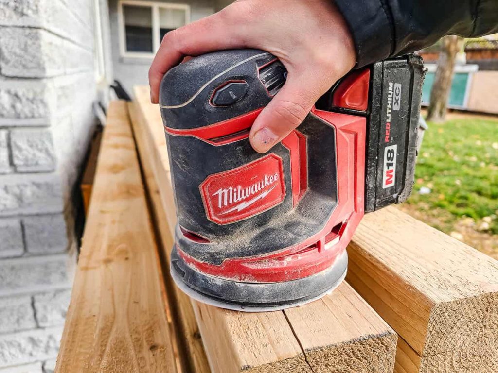 Before putting the 4x4s into the cinder blocks, sand them first using orbital sander, preparing them to be used on a bench.