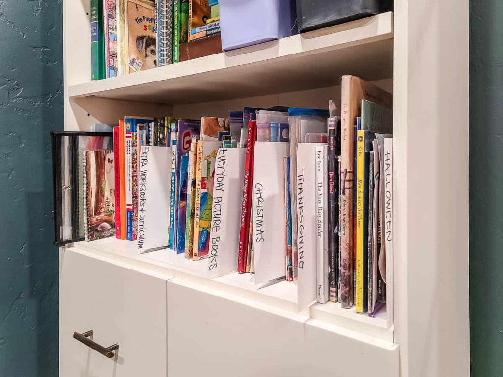 A picture of a section of the book shelf with dividers between the books made with cardstock and a Sharpie.
