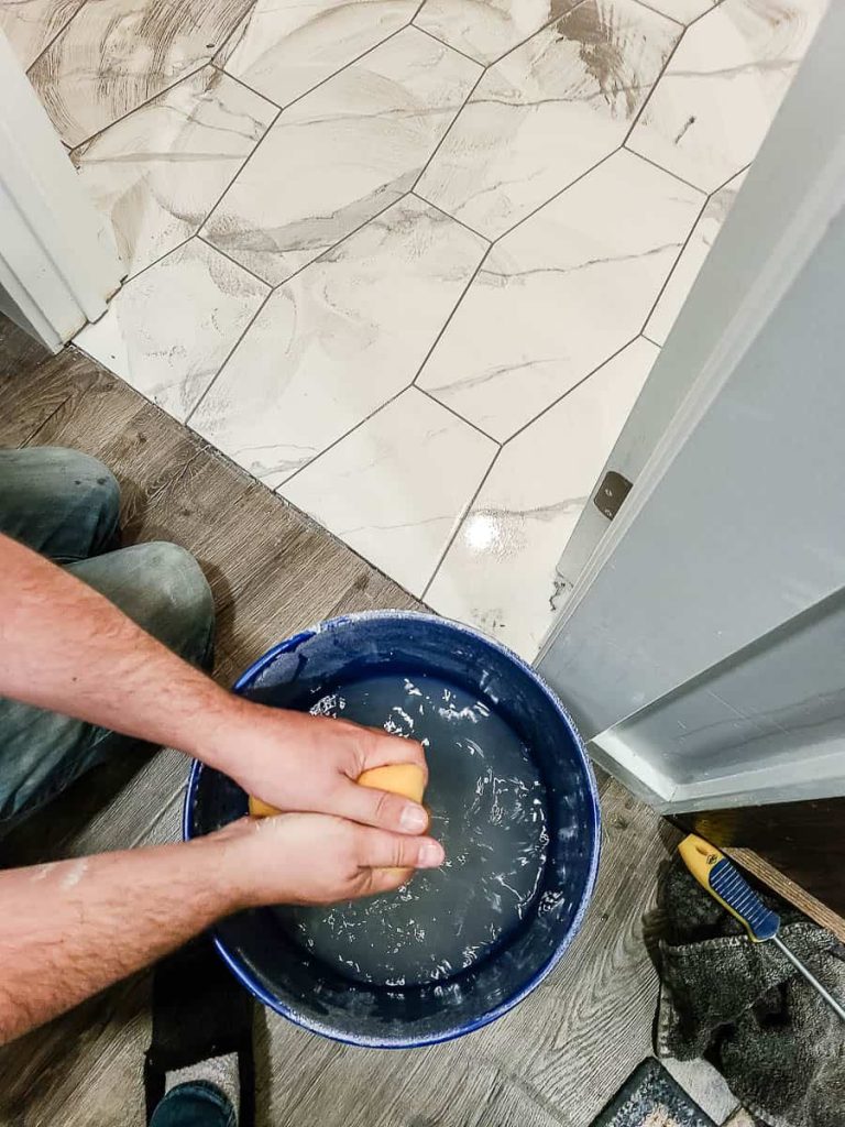 Squeezing sponge to clean tiles after grouting for finishing touches.