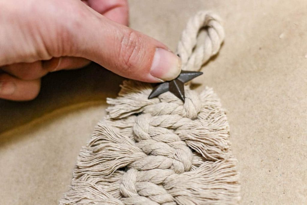 A photo of a person adding a cute star at the top of a Macrame Christmas Ornaments Tree style