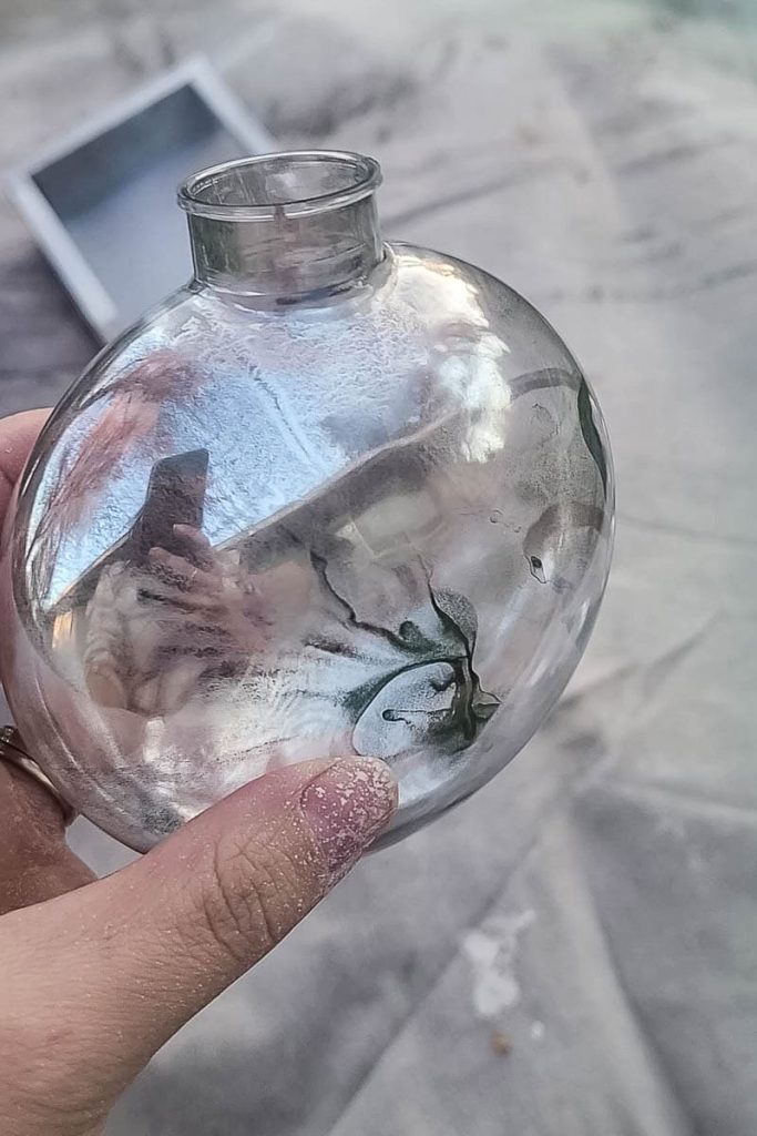 The person is holding a painted mercury glass ornamnet.