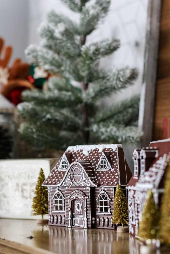 A charming gingerbread house, embellished with a glistening Dollar Tree in a luxurious gold hue adds an elegant touch to the festive setting.