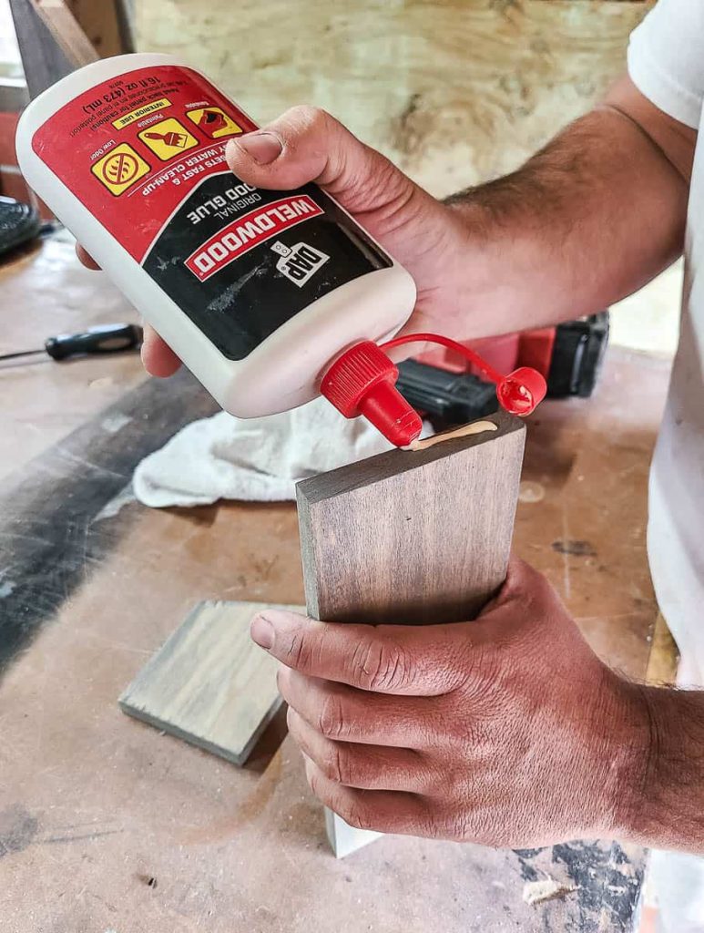 A man is gluing the edge of the wood.