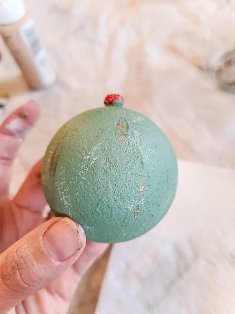 A person holds a green painted textured ornament.