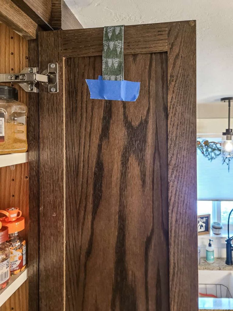 The ribbon from the mini wreath was looped into place at the back of the kitchen cabinet and secured with painter's tape
