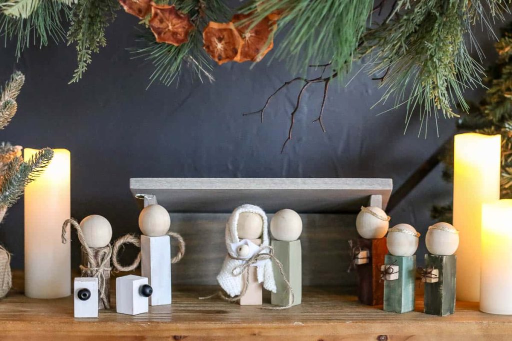 A photo of a 6 handmade wooden dolls arranged with candle on each side.